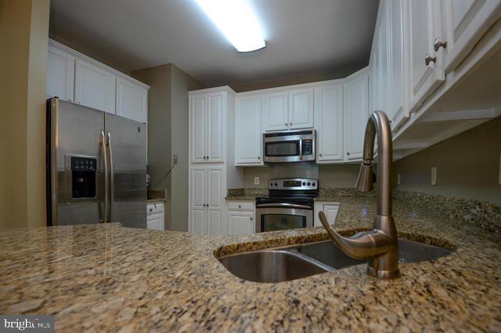 9404 Regency Crest Drive Vienna, VA 22181 - Photo 11 of 25 a kitchen with kitchen island granite countertop a sink refrigerator and microwave