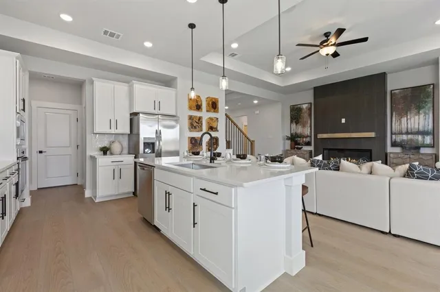a large white kitchen with a stove a sink a refrigerator and a fireplace