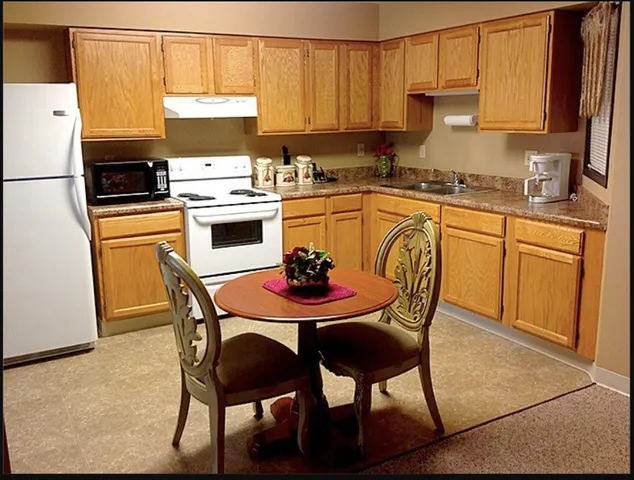 a kitchen with stainless steel appliances a table chairs and a refrigerator