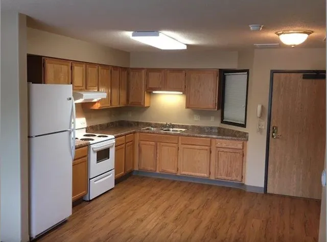 a kitchen with granite countertop a refrigerator stove and wooden floor