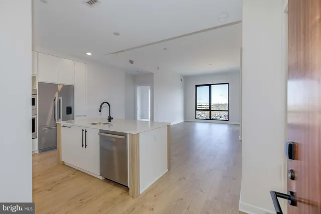 a view of kitchen with stainless steel appliances a refrigerator and wooden floor
