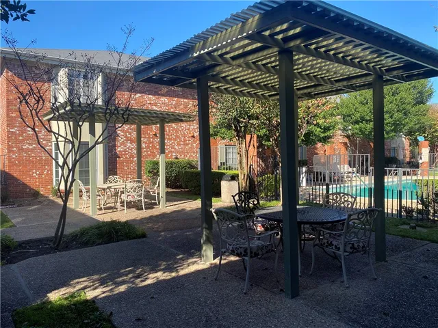 a view of a patio with table and chairs potted plants and floor to ceiling window