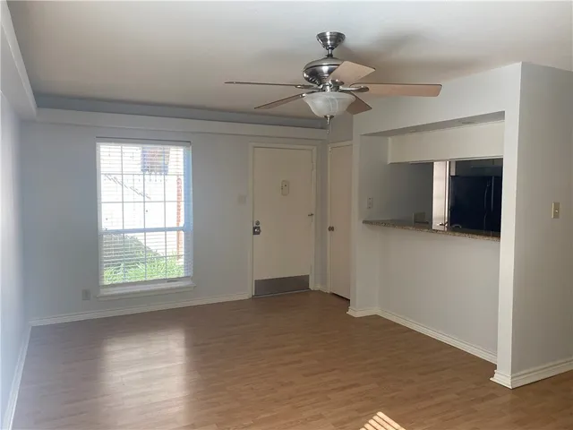 an empty room with wooden floor chandelier fan and windows