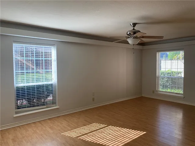 a view of an empty room with a window and wooden floor