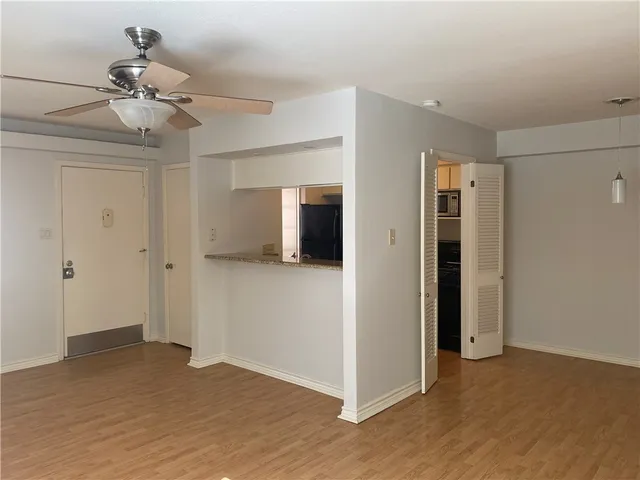a view of a big room with wooden floor and chandelier fan