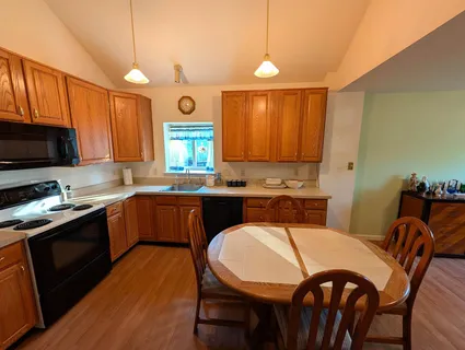 a large kitchen with granite countertop a stove a sink a dining table and chairs