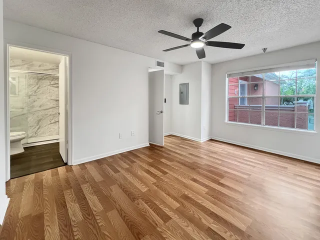 a view of empty room with wooden floor and fan