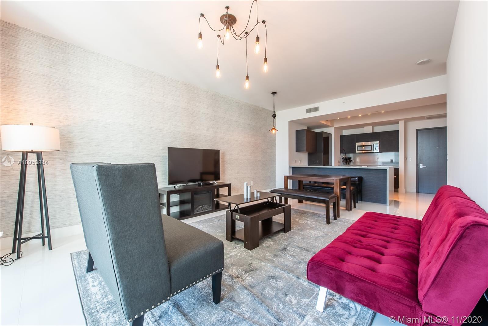 a living room with furniture a flat screen tv and kitchen view