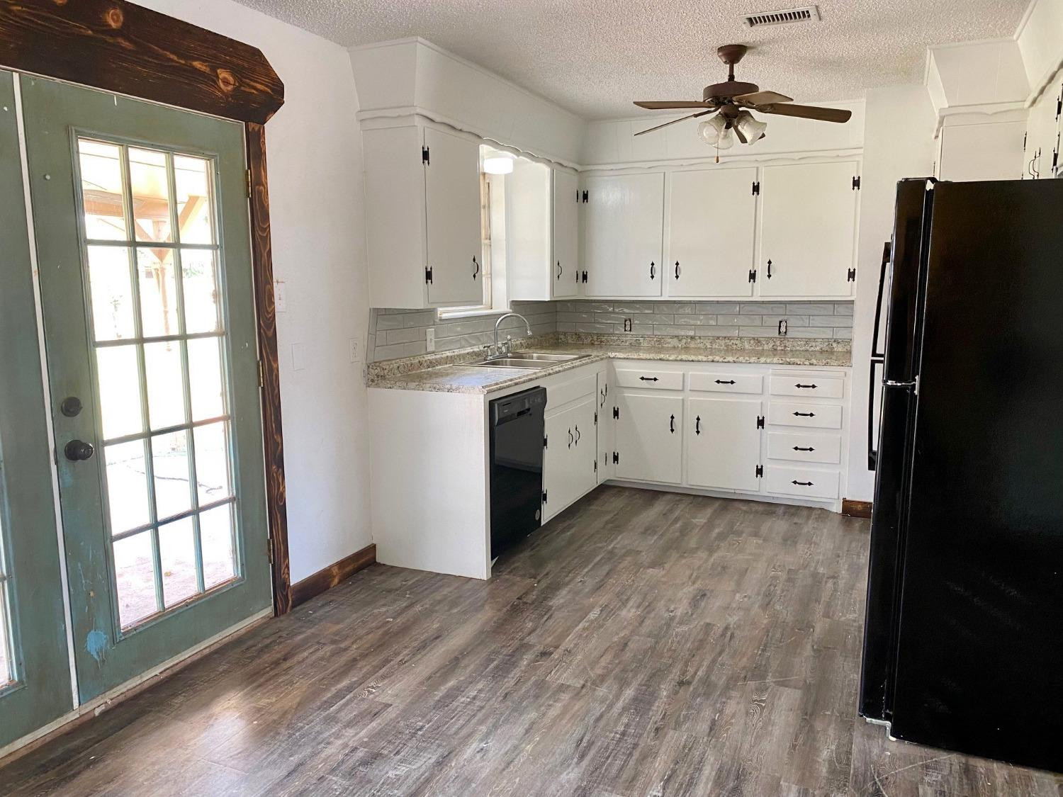 215 Darrell Street Levelland, TX 79336 - Photo 5 of 9 a kitchen with a refrigerator a sink and dishwasher with wooden floor