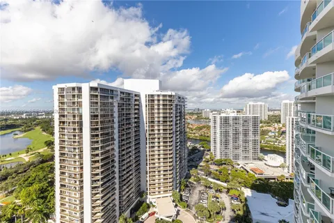 an aerial view of a tennis ground and a yard view of a house