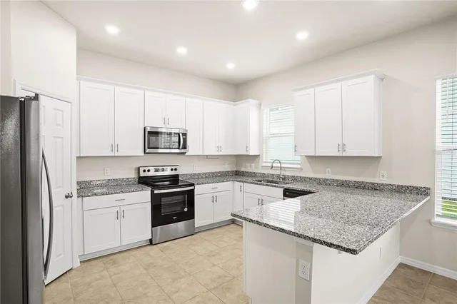 a kitchen with a sink a stove a refrigerator and white cabinets