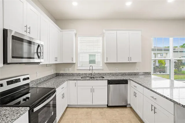 a white kitchen with granite countertop a stove top oven microwave and cabinets