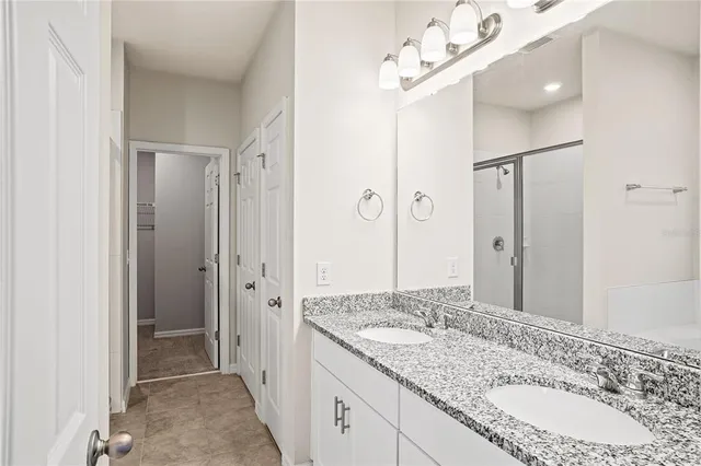 a bathroom with a granite countertop sink a mirror and a shower