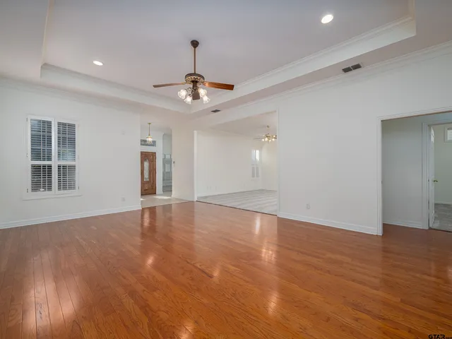 a view of an empty room with wooden floor and window