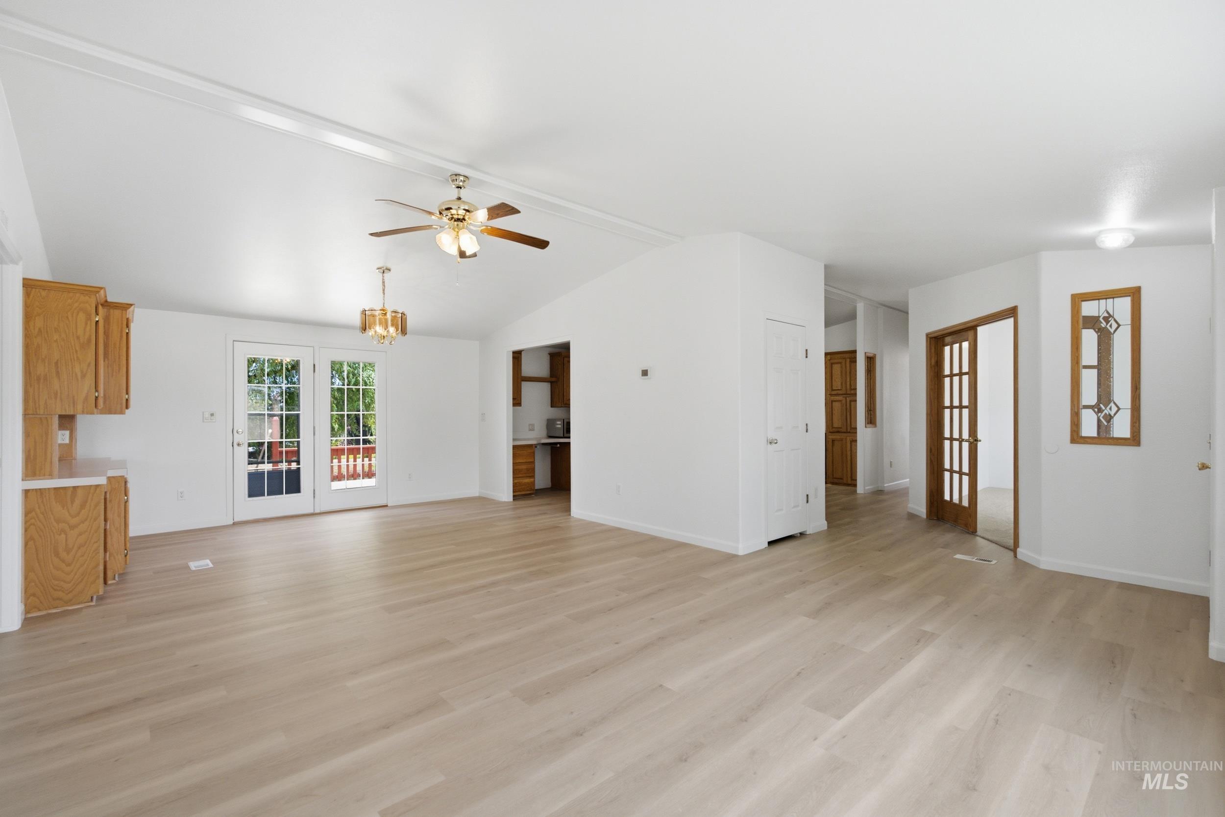 7422 Track Road Nampa, ID 83686 - Photo 14 of 50 Open-concept living area featuring light wood-finish flooring, vaulted ceilings, and a ceiling fan with integrated lighting