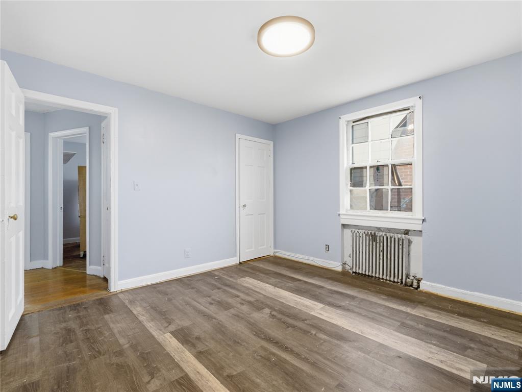 153 Arlington Avenue Paterson, NJ 07502 - Photo 4 of 12 a view of an empty room with wooden floor and a window