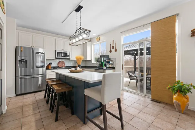 a kitchen with stainless steel appliances granite countertop a refrigerator a sink a stove and white cabinets