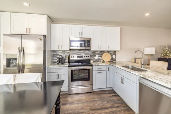 a kitchen with stainless steel appliances granite countertop a stove a sink and a refrigerator