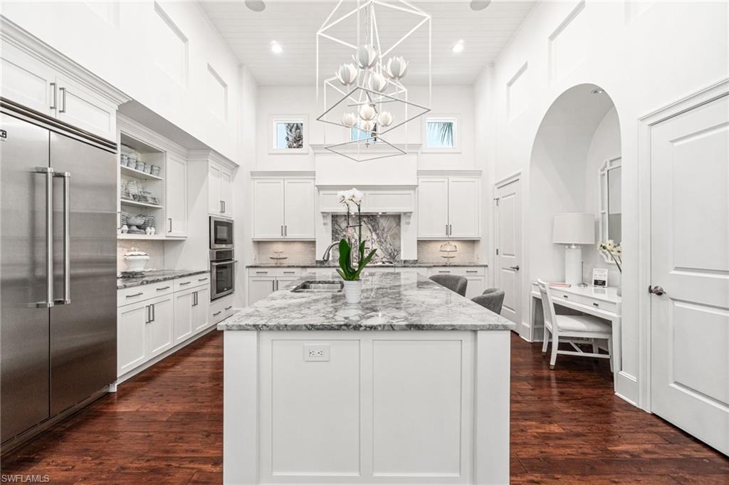 16755 Lucarno Way Naples, FL 34110 - Photo 7 of 50 a kitchen with stainless steel appliances granite countertop a refrigerator a sink dishwasher a dining table and chairs with wooden floor