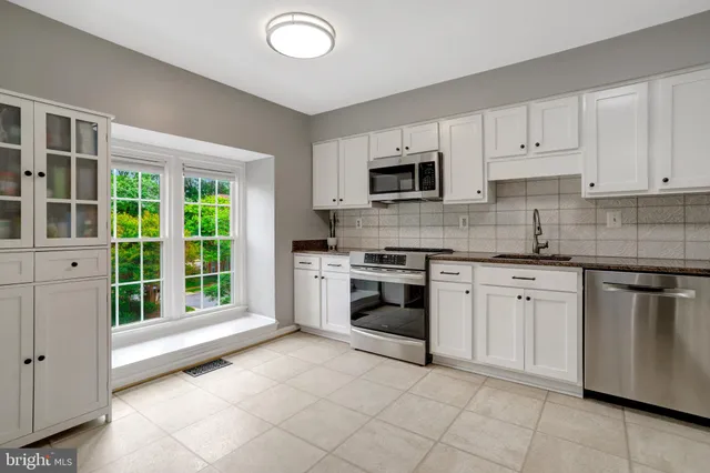 a kitchen with granite countertop a stove top oven sink and cabinets