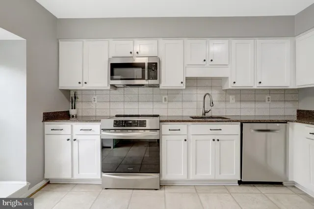 a kitchen with white cabinets and stainless steel appliances