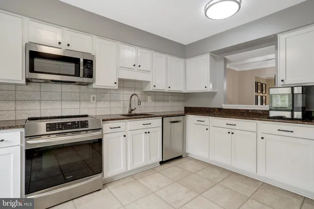 a kitchen with granite countertop white cabinets stainless steel appliances and a sink
