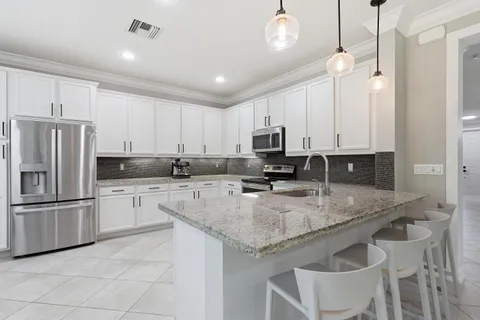 a kitchen with granite countertop a refrigerator sink and cabinets
