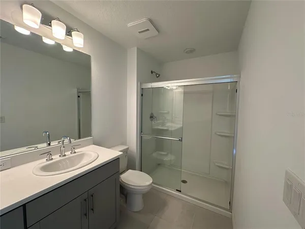 a bathroom with a shower sink vanity and toilet