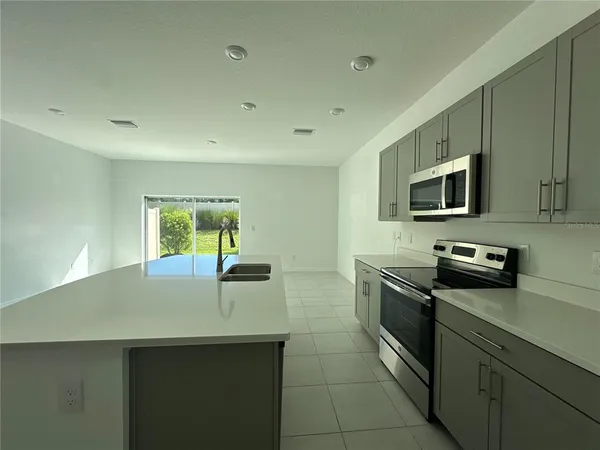 a kitchen with a sink a counter top space appliances and cabinets