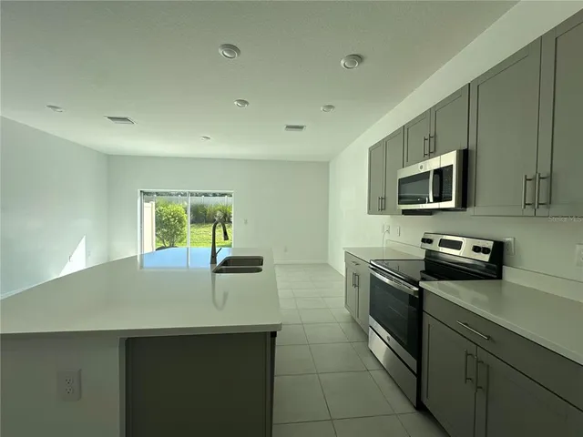 a kitchen with a sink a counter top space appliances and cabinets