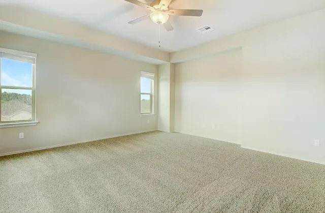 an empty room with windows and fan