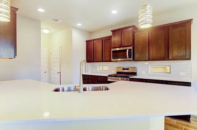a kitchen with stainless steel appliances granite countertop a sink stove and microwave