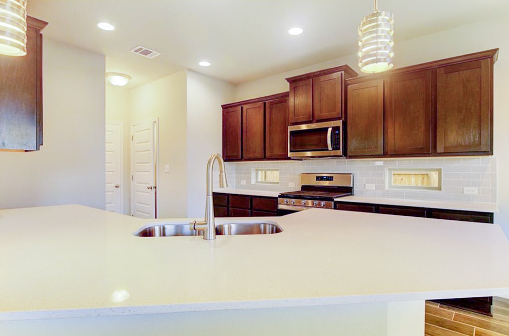 3453 Pauling Loop Round Rock, TX 78665 - Photo 7 of 28 a kitchen with stainless steel appliances granite countertop a sink stove and microwave