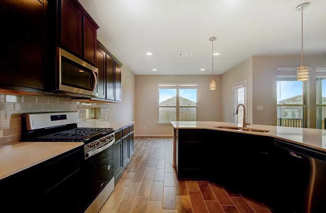 a kitchen with stainless steel appliances a sink dishwasher a stove and a microwave oven on granite countertops