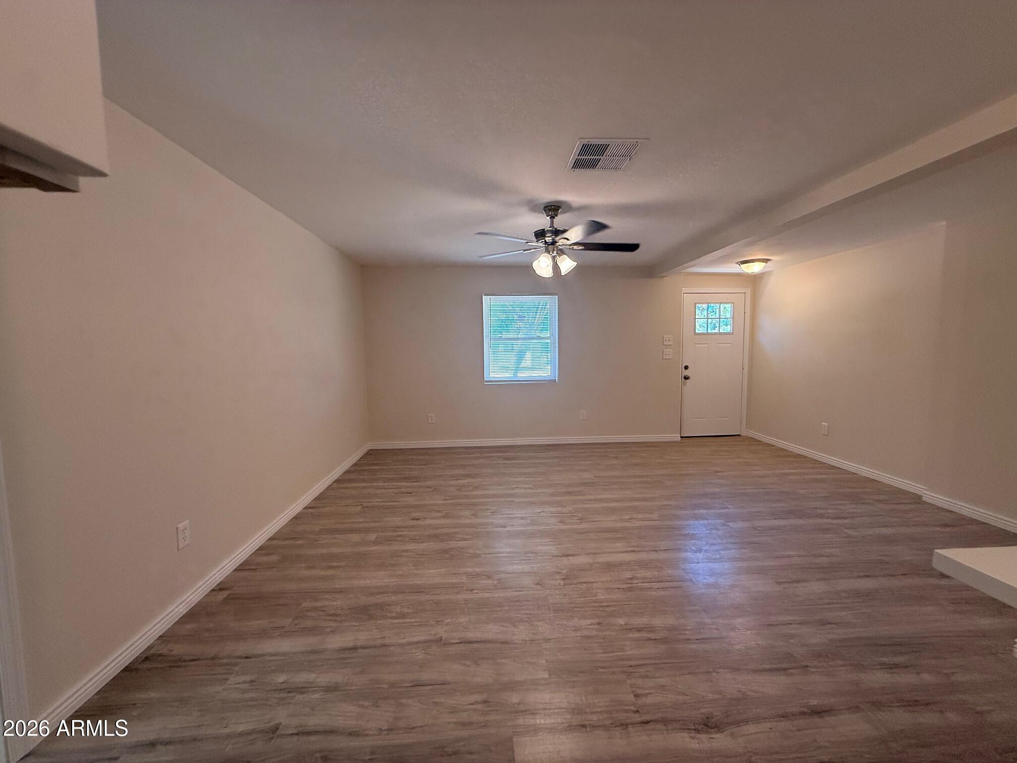 135 Rex Avenue Apache Junction, AZ 85120 - Photo 16 of 27 a view of an empty room with window and wooden floor