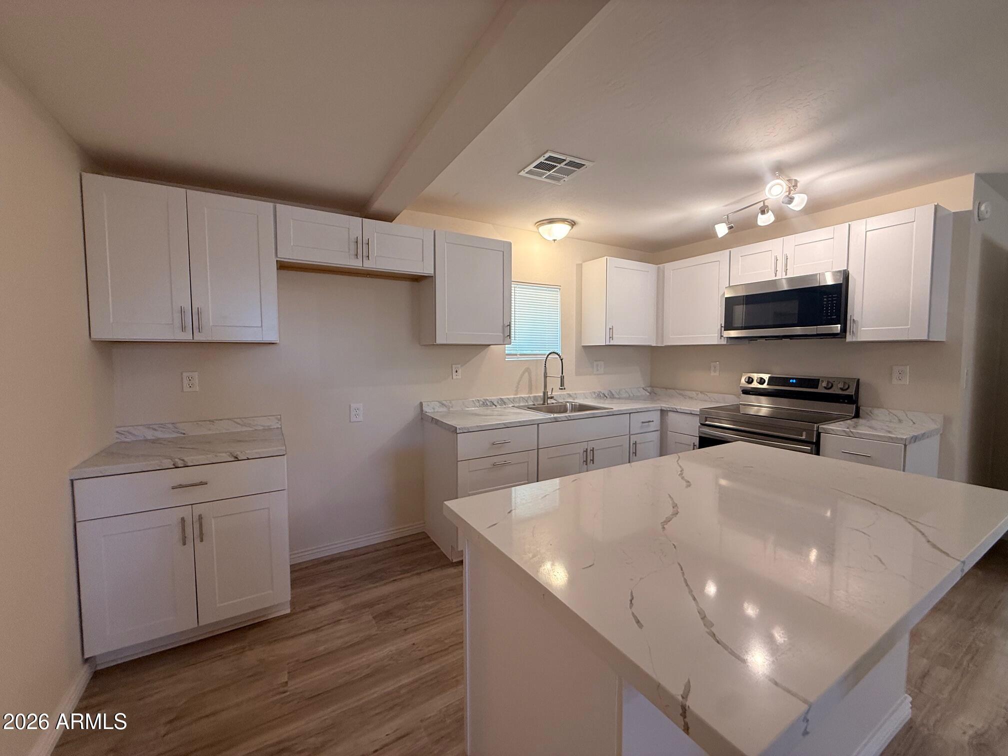 135 Rex Avenue Apache Junction, AZ 85120 - Photo 19 of 27 a kitchen with a sink a microwave a stove and cabinets