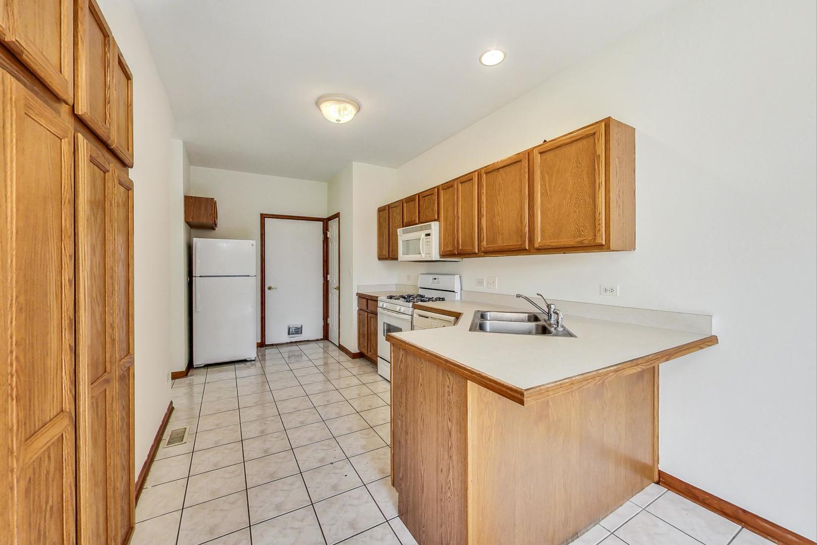 565 Goodwin Drive Bolingbrook, IL 60440 - Photo 12 of 44 a kitchen with a sink a stove cabinets and a refrigerator