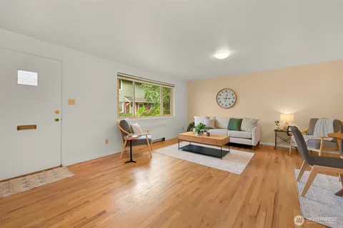 a living room with furniture and a dining table with wooden floor