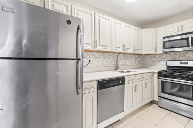 a white refrigerator freezer sitting inside of a kitchen with stainless steel appliances granite countertop cabinets and a refrigerator