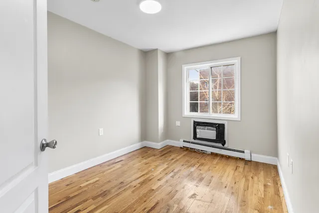 an empty room with windows and fireplace