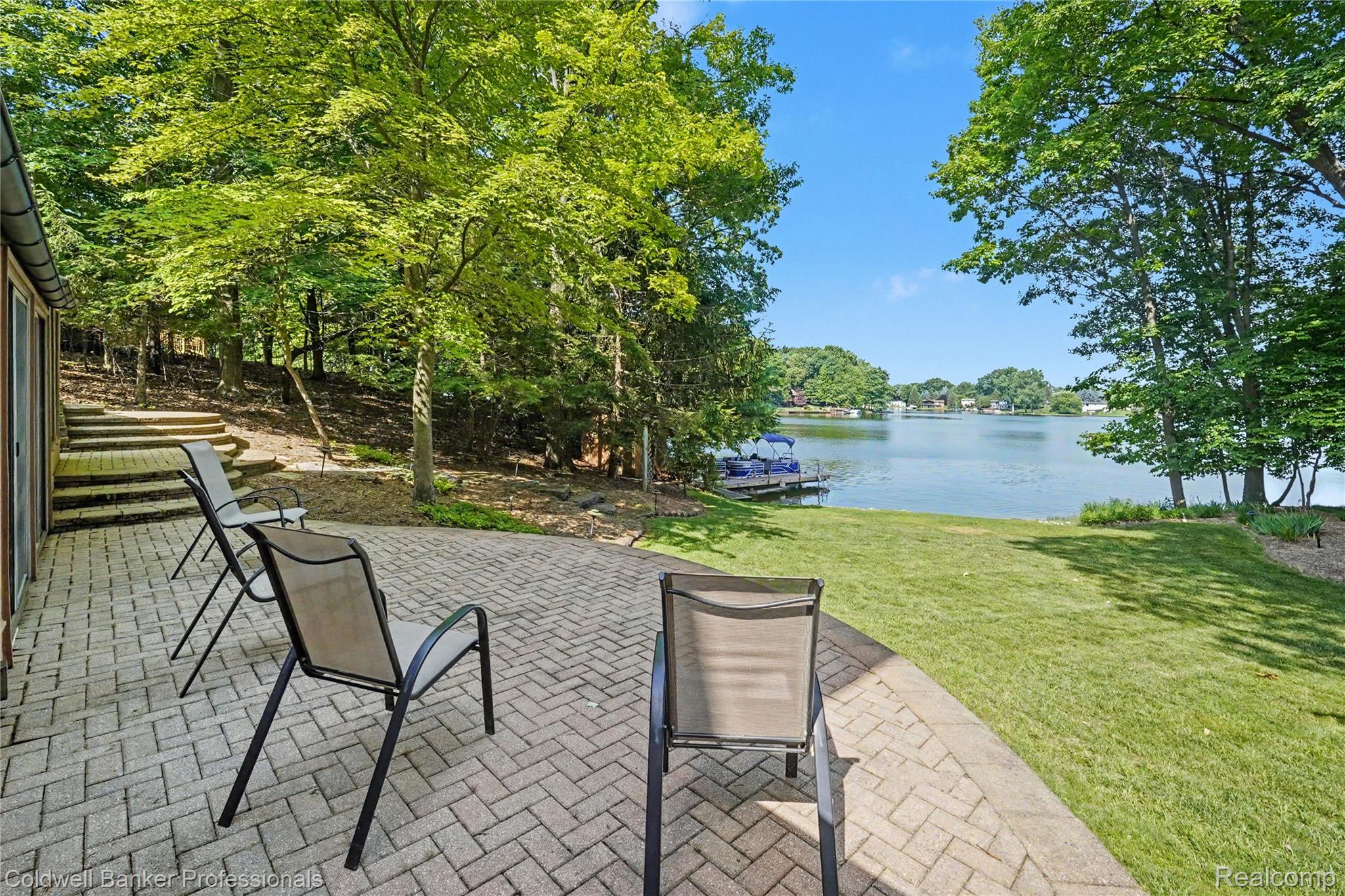 3583 Mitchell Road Metamora, MI 48455 - Photo 9 of 58 Paver patio extending to a manicured lawn, bordered by mature trees and a substantial body of water