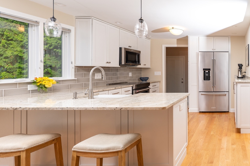 5 Crest Road Natick, MA 01760 - Photo 7 of 36 a kitchen with stainless steel appliances granite countertop a sink a stove a refrigerator a dining table and chairs with wooden floor