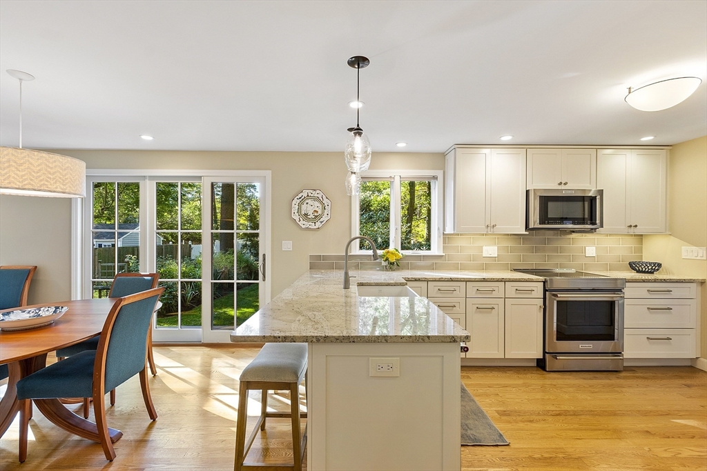 5 Crest Road Natick, MA 01760 - Photo 8 of 36 a kitchen with stainless steel appliances granite countertop a stove top oven a sink dishwasher a dining table and chairs with wooden floor