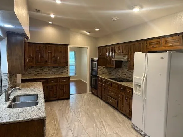 a kitchen with stainless steel appliances granite countertop a refrigerator and a sink