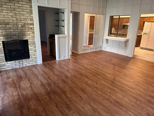 a view of an empty room with wooden floor and a fireplace