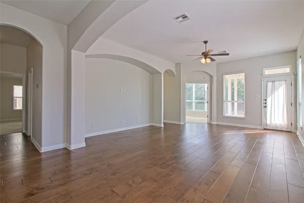 an empty room with wooden floor chandelier and windows