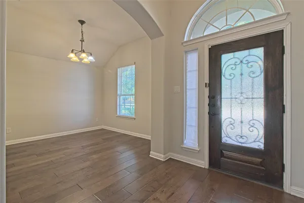 an empty room with wooden floor closet and windows