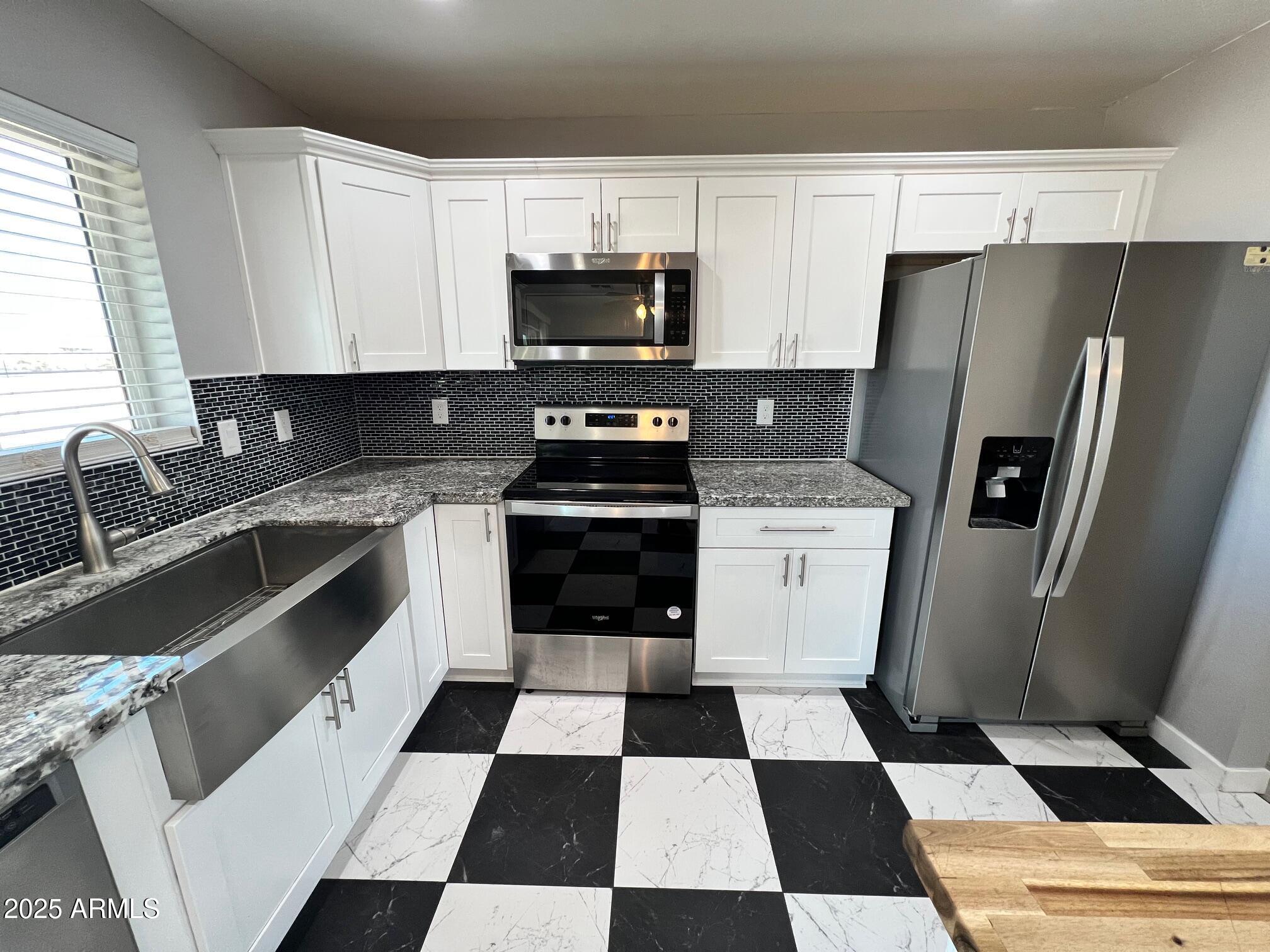 4552 North Loring Road Casa Grande, AZ 85194 - Photo 7 of 48 a kitchen with a checkered floor and white cabinets