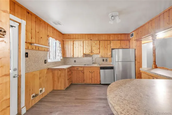 a kitchen with a refrigerator a sink and dishwasher with wooden floor