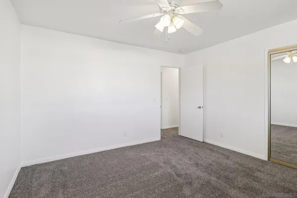 an empty room with a window and a fan